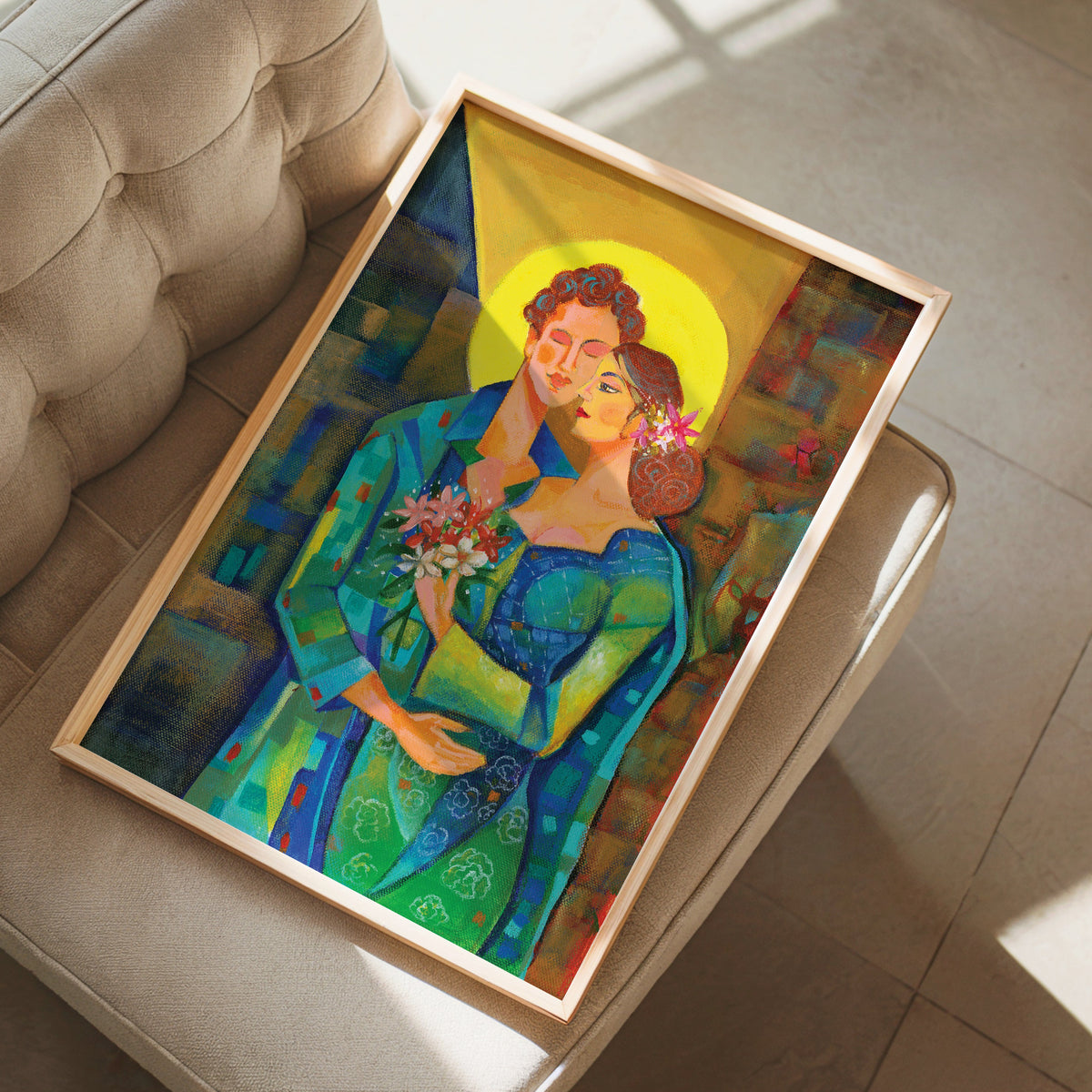 A framed art print depicting a stylized couple with a golden halo, resting on a beige tufted armchair in a sunlit room.